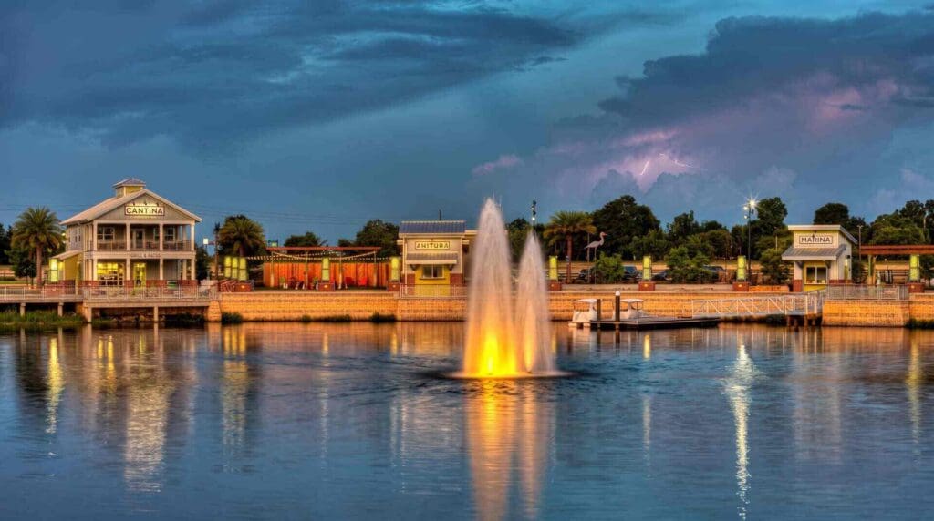 Center Lake Park in Oviedo FL at dusk with glowing fountains, calm waterfront reflections, and softly lit pavilion buildings, supporting local garage door repair relevance.
